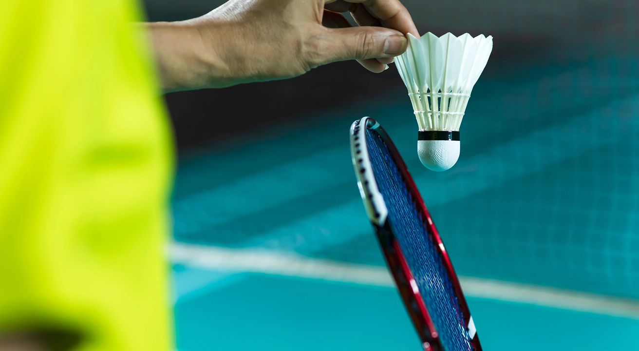 Students playing badminton outdoors on campus court