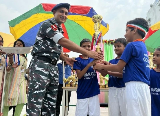 Officer in military uniform presenting championship trophy to student football players in blue jerseys