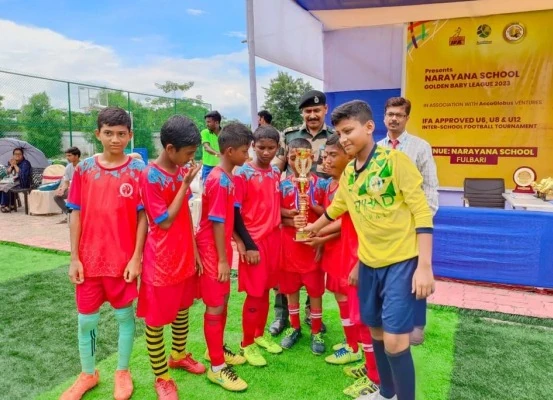 Officer and school faculty presenting trophy to junior football team in red jerseys at tournament
