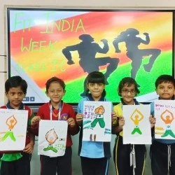 Junior students holding up Fit India yoga drawings in front of a smart board