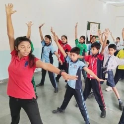 Physical education instructor leading students in an indoor stretching session