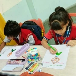 Two primary students sitting at a desk coloring yoga posture drawings